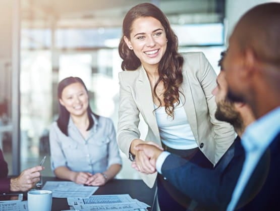 female in business suit shaking hands with a male colleague