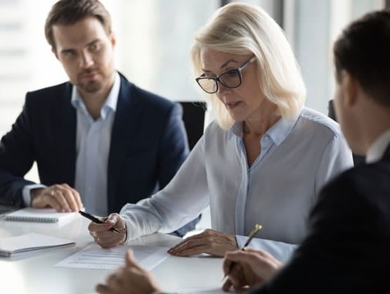 A business woman reviewing documents with two subordinates.