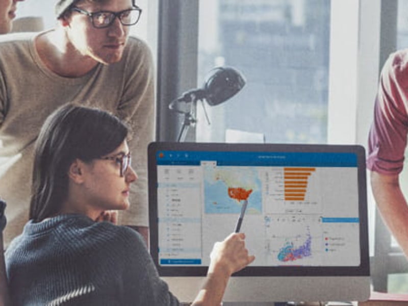 People looking at a screen with graphs and maps.