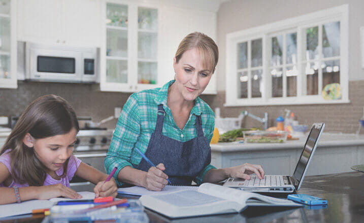 female_student_and_daughter_studying_at_table_in_kitchen