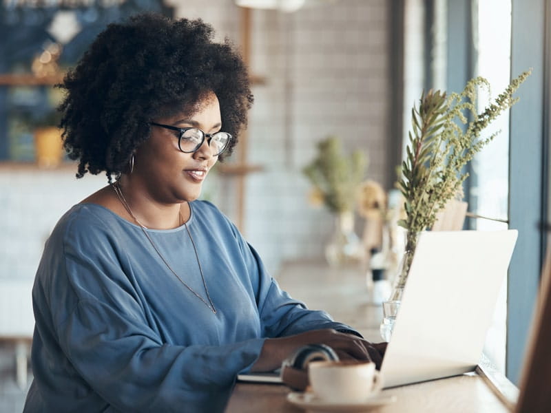 a female student using her laptop in an indoor coffee shop