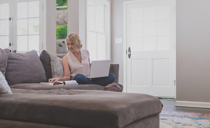 female_student_studying_on_couch_with_laptop_at_home