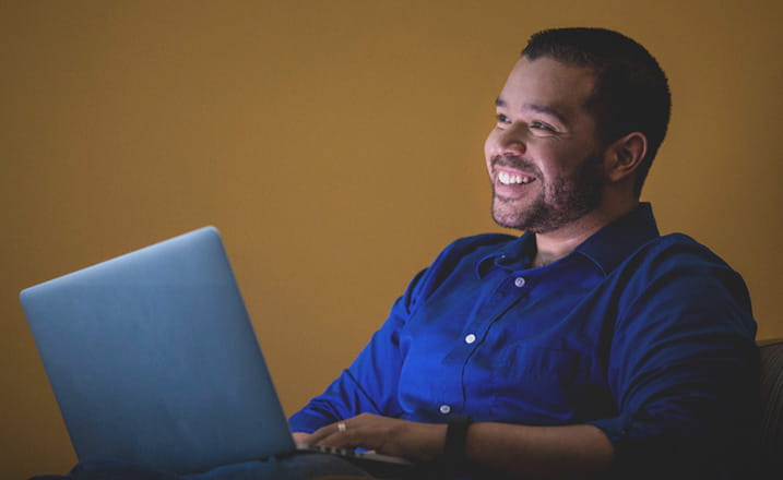 male_student_with_laptop_looking_up_smiling