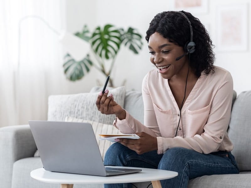 young female student interacting on laptop with headset on