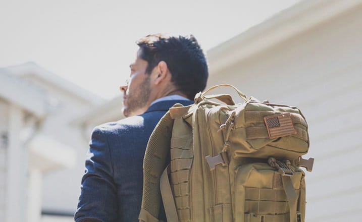 military_male_student_wearing_backpack_american_badge_outside_daylight