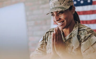 military woman in uniform smiling behind the American flag