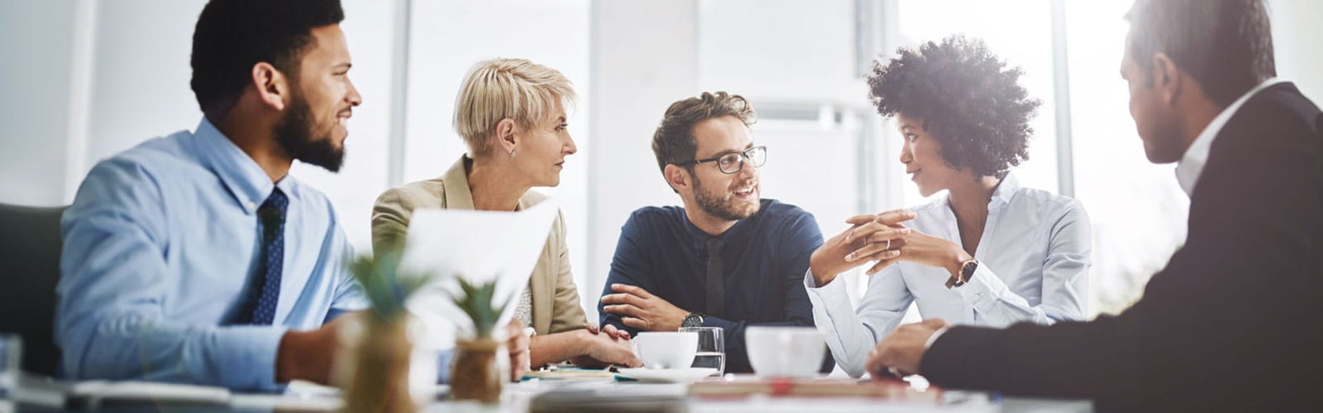 group of colleagues in a room discussing information with a trainer