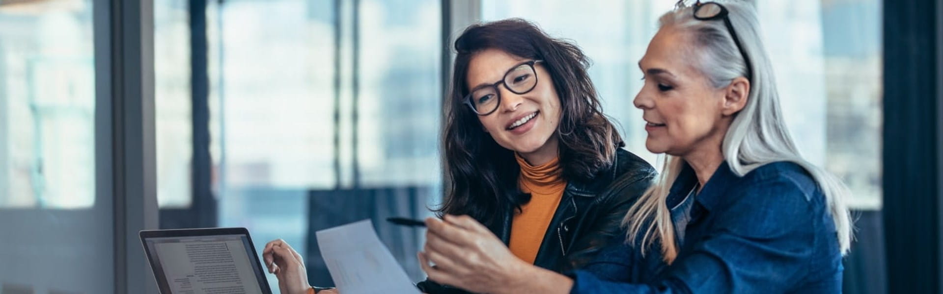 female mentor helping young asian female coworker