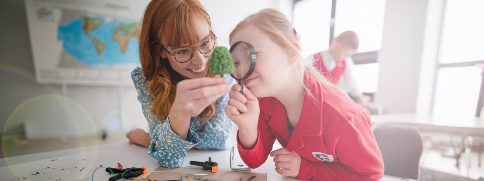 female teacher using a microscope with a special needs female elementary school child