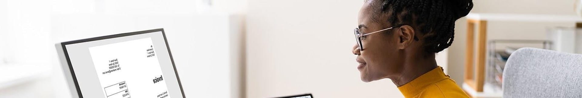 accounting student working on laptop and computer looking at invoice