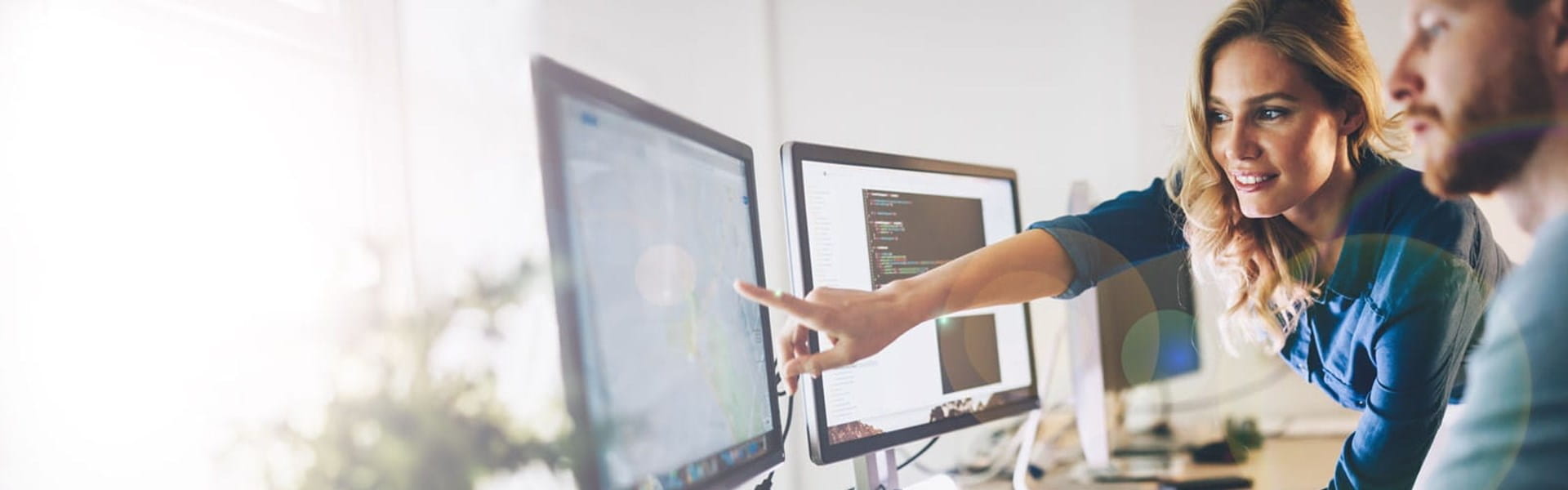 manager showing IT professional an item on a desktop screen