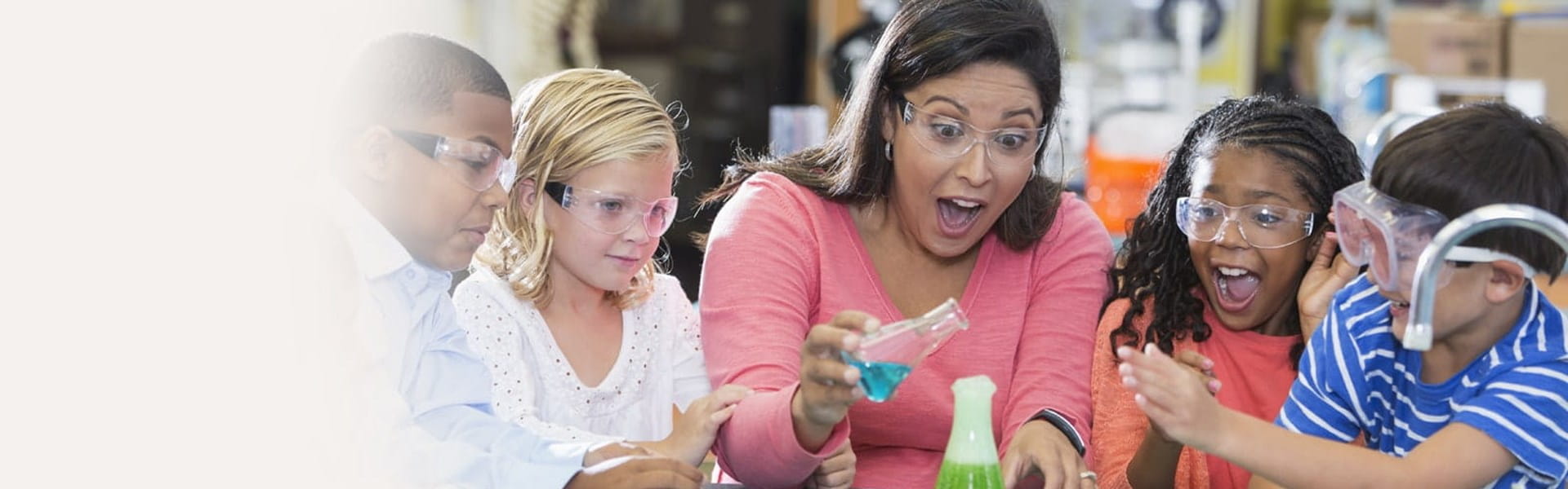 Teacher using flasks in a science experiment with children watching excitedly.