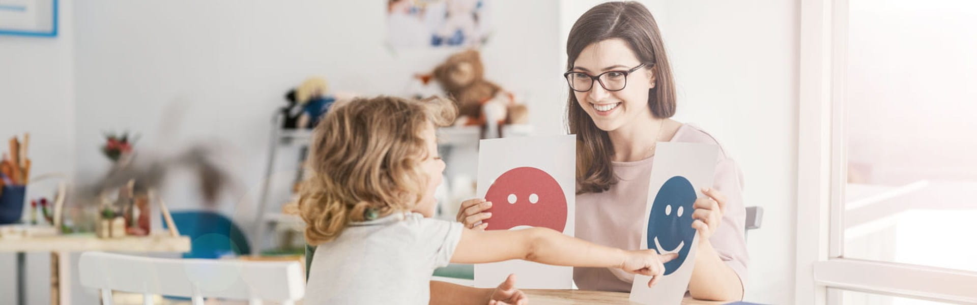 female psychologist working with a child and showing pictures on emotions