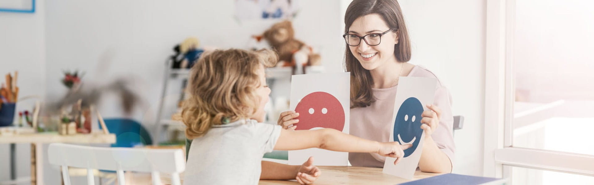 female psychologist working with a child and showing pictures on emotions