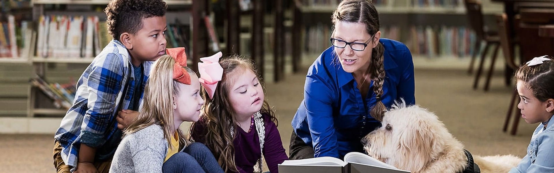 special education teacher reading to a group of children and their support dog