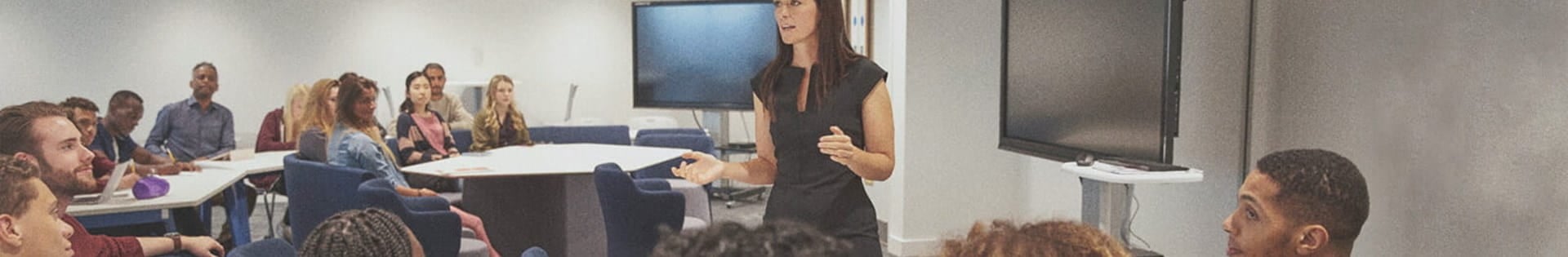 female teacher lecturing students about teaching curriculum in classroom