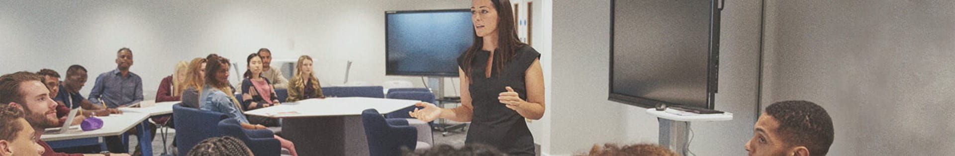 female teacher lecturing students about teaching curriculum in classroom