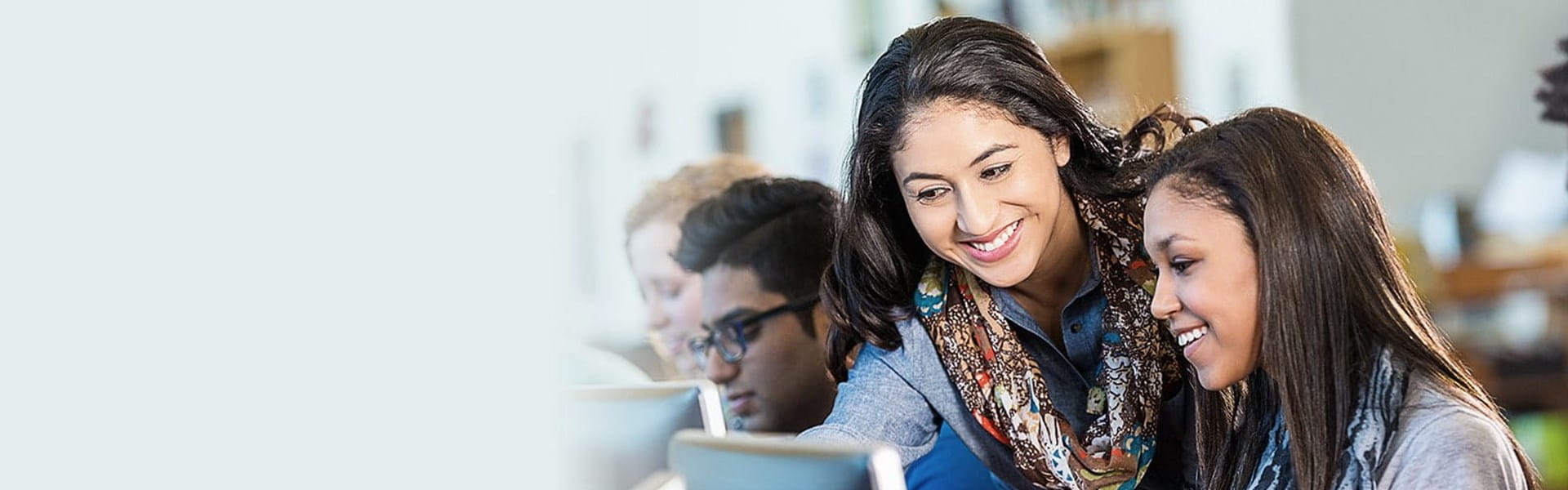 High school teacher assisting a student at a computer.