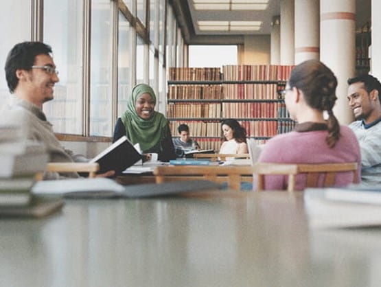 international business students studying together at table in library