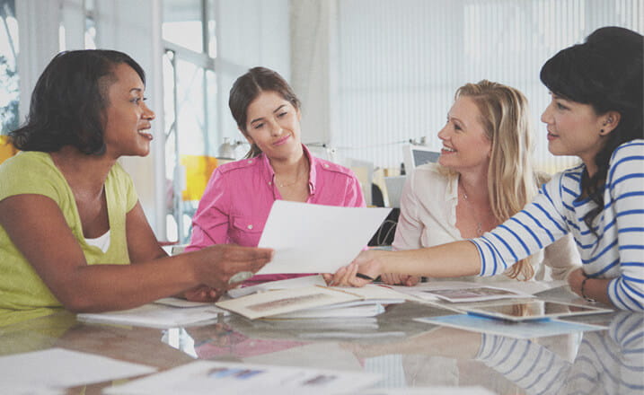 four female project management students sitting at a table discussing work