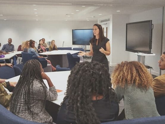 female teacher lecturing students about teaching curriculum in classroom