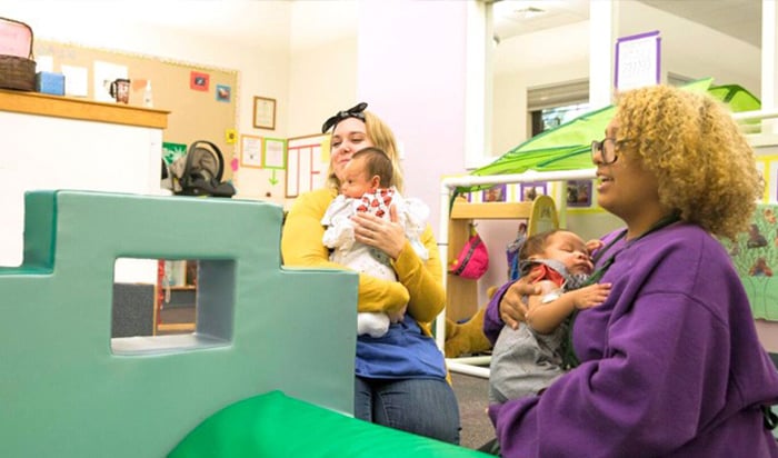 Two women holding infants at the Child Study Center at Los Medanos College.