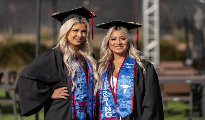 Class of 2022 nursing graduates Sonia and Homa Sher standing next to each other wearing their regalia.