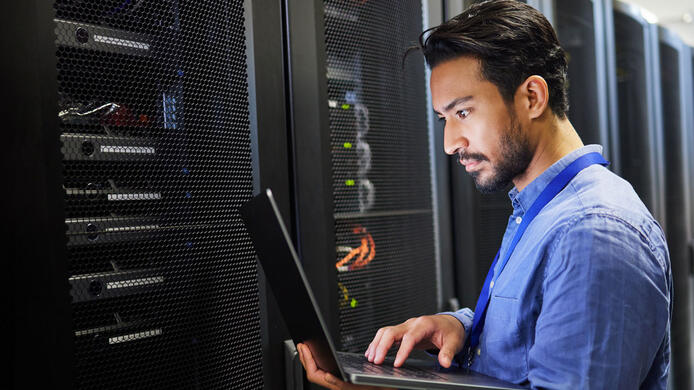Programming, data center and a man with a laptop for maintenance, cyber security and internet check. Coding, email and an Asian programmer typing on a computer for network or server analytics