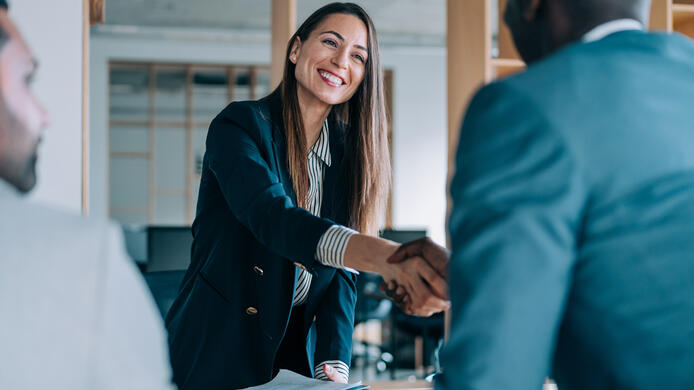 Business people shaking hands in the office. Group of business persons in business meeting. Three entrepreneurs on meeting in board room. Corporate business team on meeting in modern office. Female manager discussing new project with her colleagues. Company owner on a meeting with two of her employees in her office.