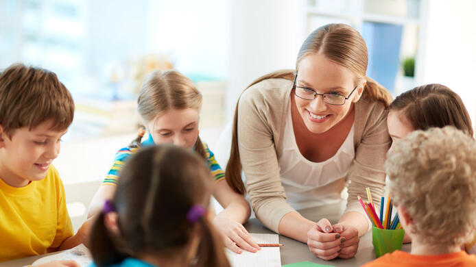 Portrait of diligent schoolkids and their teacher talking at lesson