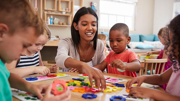 Teacher And Pupils Using Flower Shapes In Montessori School