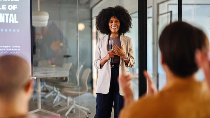 Black woman leading a panel discussion about sustainability in the office