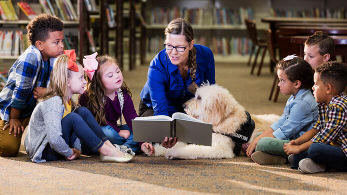 Kindergarten teacher reading a book to several children