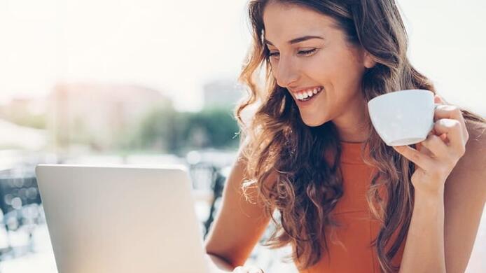 woman on her laptop at a cafe drinking coffee outdoors
