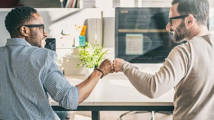 Two coworkers celebrating with a fist bump.