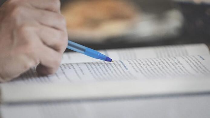 hand_holding_pen_studying_with_textbook_daylight_macros_1_662_717x440.jpg