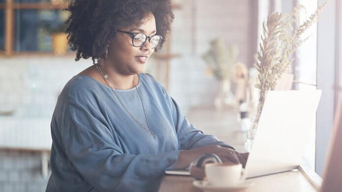 female student working in a coffee shop on her laptop