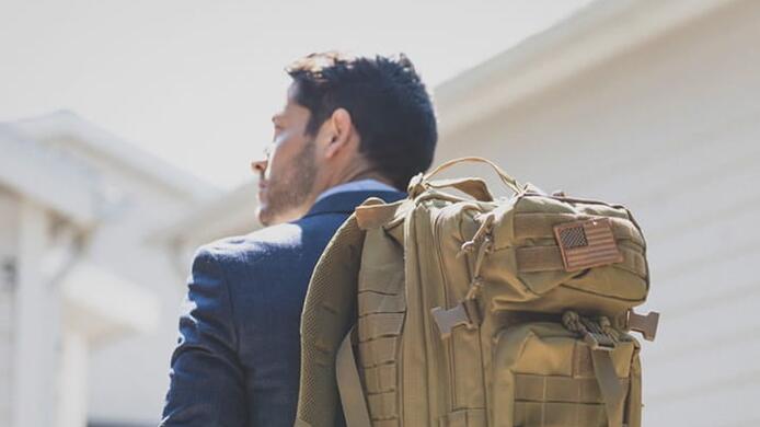 military_male_student_wearing_backpack_american_badge_outside_daylight
