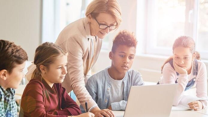 older female teacher who has her credential teaching a group of older elementary school children