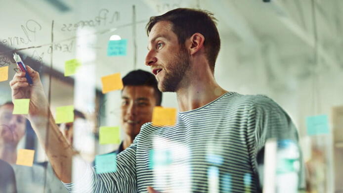 group of workers brainstorming on a transparent board with sticky notes