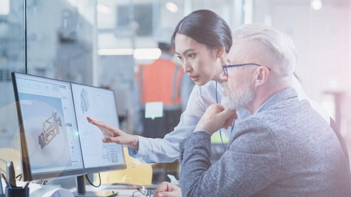 young asian female coworker helping an older gentleman visualize an object related to data science on a computer screen