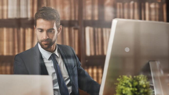 male paralegal student studying surrounded by textbooks in a library