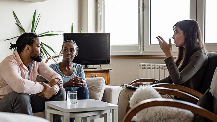 female psychologist talking to married couple in counseling session