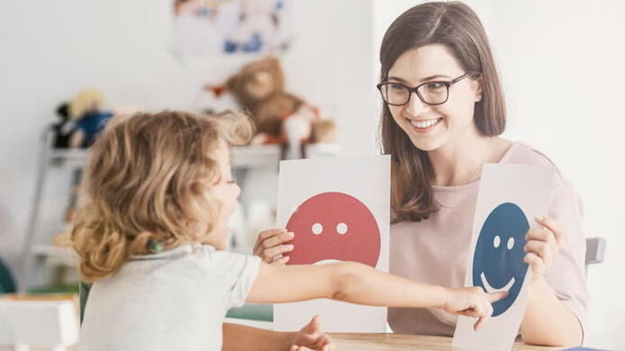 female psychologist working with a child and showing pictures on emotions