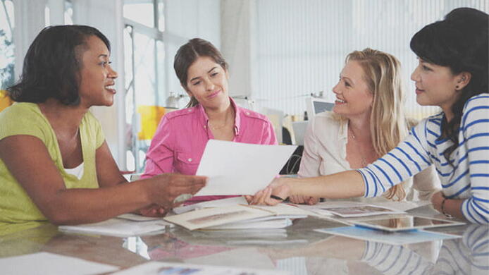 four female project management students sitting at a table discussing work