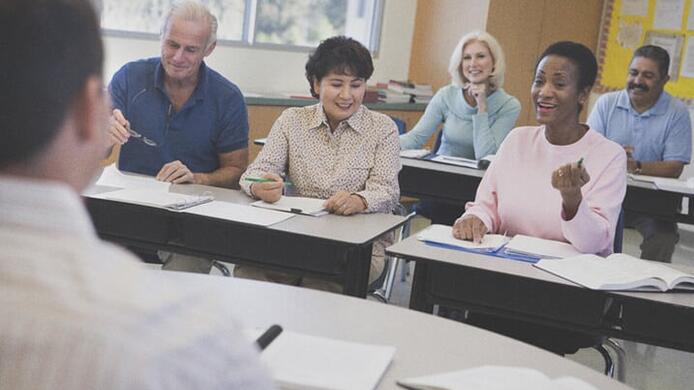students talking to spanish teaching faculty member who is in front of classroom