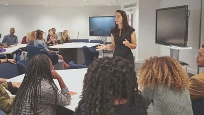 female teacher lecturing students about teaching curriculum in classroom