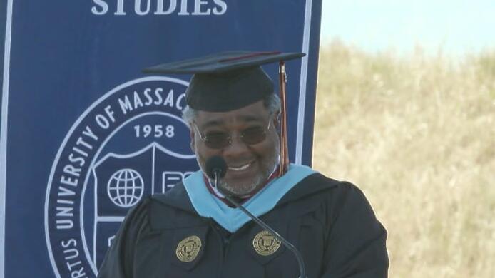 Northern California Commencement speaker David Earl Cobb IV delivering his speech wearing graduation regalia.