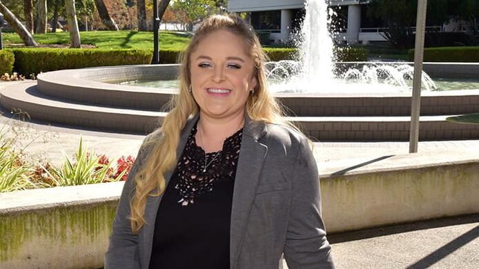 A portrait of Class of 2021 graduation candidate Doreen Temple with a fountain in the background.