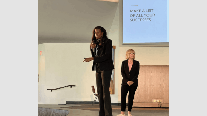 Dr. Rebecca Pianta, a university alum, holds a microphone while delivering a presentation alongside faculty member Dr. Marilou Ryder.